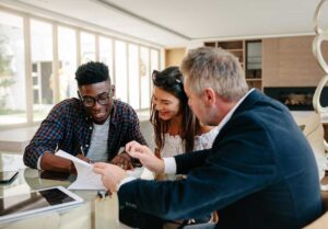 Parents review household finances and life insurance documents at a kitchen table with a child nearby.