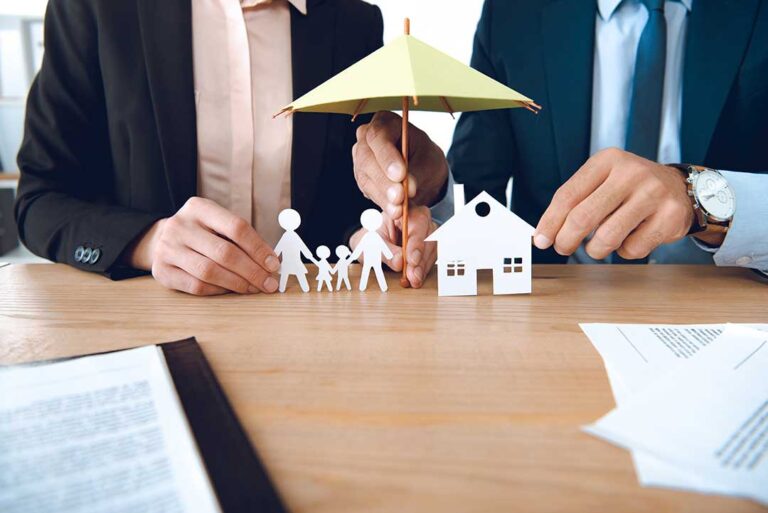 A couple reviews life insurance documents at a kitchen table with a calculator and household budget nearby.